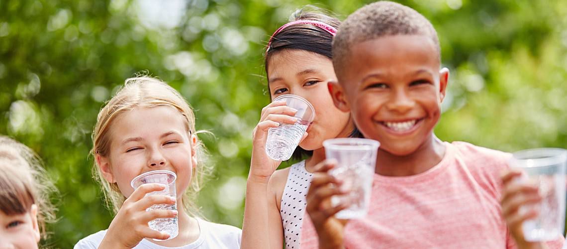 Group of children drinking water from cups.