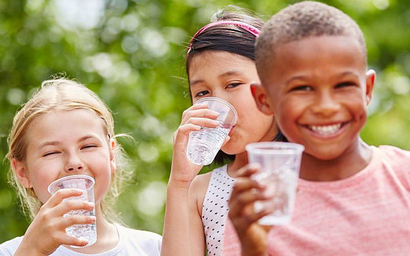 Group of children drinking water from cups.